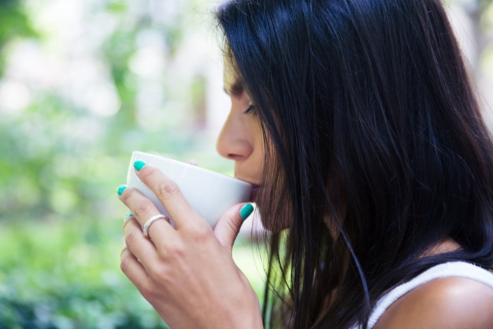 Side view portrait of a woman drinking coffee outdoors