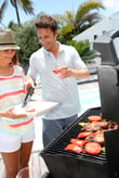 Cheerful couple in holidays preparing grilled meat